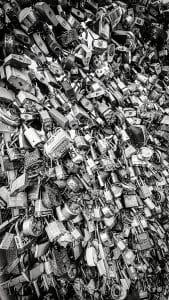 The Old Port Lock Wall in Portland, Maine, is a captivating installation where countless padlocks adorn a section of fencing, each lock symbolizing a personal story or commitment. This striking black-and-white photograph emphasizes the intricate details and varying shapes of the padlocks, creating a visually engaging texture. The dense collection of locks, representing love, memory, and individual stories, adds a unique character to the urban landscape and serves as a modern testament to personal and collective sentiments.