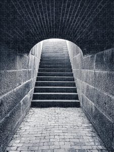 Echoing Steps Puzzle by Blaine Stoner featuring a black-and-white image of a staircase leading up from a dimly lit tunnel.