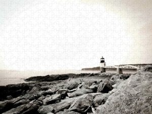 A jigsaw puzzle featuring a vintage-inspired image of Marshall Point Lighthouse, with a muted palette and a rocky shoreline leading to the distant horizon.