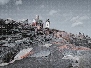 Photograph of Pemaquid Point Lighthouse with a color pop effect, highlighting the lighthouse and surrounding buildings against a muted rocky landscape, captured by Blaine Stoner.