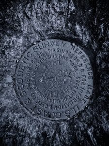 A geodetic survey marker rests in the granite summit of Blue Hill Mountain, standing as a testament to precision and endurance.