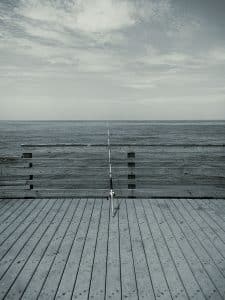 A solitary fishing rod stands ready at Venice Beach Fishing Pier, Florida — a quiet moment between patience and the thrill of the catch. The scene captures the timeless connection between the angler and the sea.