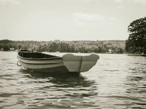 A small boat rests quietly on the high tide in Blue Hill Bay, Maine. The timeless composition reflects a peaceful moment on the water.