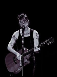 John Rzeznik of the Goo Goo Dolls playing acoustic guitar and singing on stage in Bangor, Maine, August 2025.