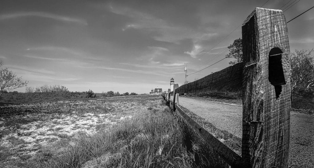 A weathered fence leads the way to Highland Light, Cape Cod’s oldest beacon. Standing against the sky, it tells a timeless story of strength and the sea.